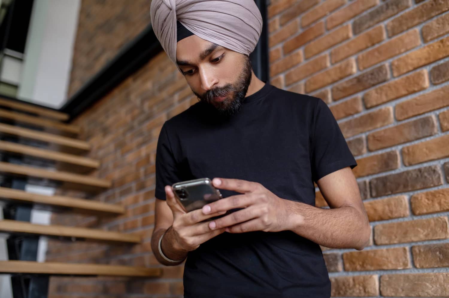 young man black tshirt texting phone looking involved
